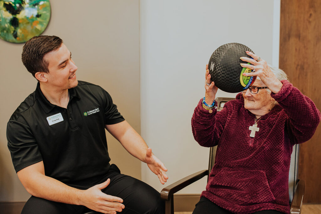 physical therapist helping a guest use a medicine ball