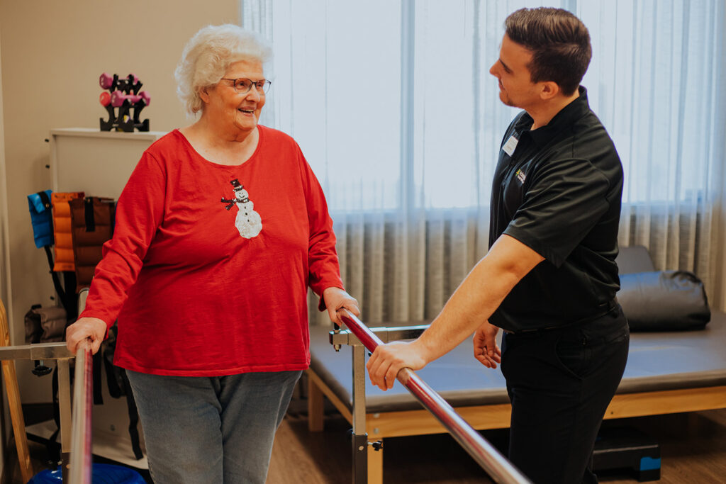 Elderly woman using parallel bars in physical therapy