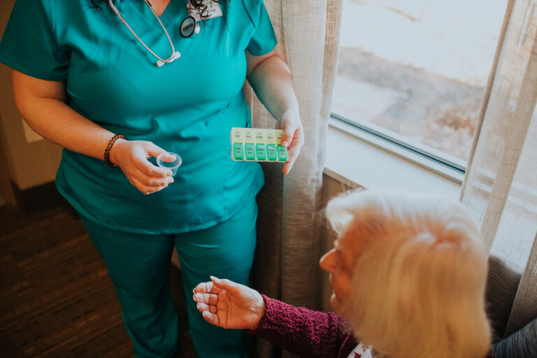 woman being handed pills from a case by a nurse