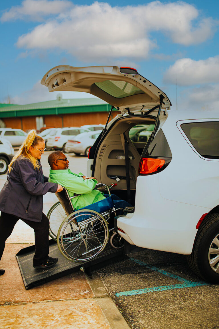 IADC staff member pushes guest in wheelchair into accessible van.