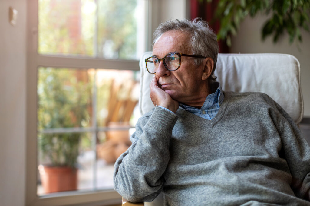 Lonely older man looks out the window.